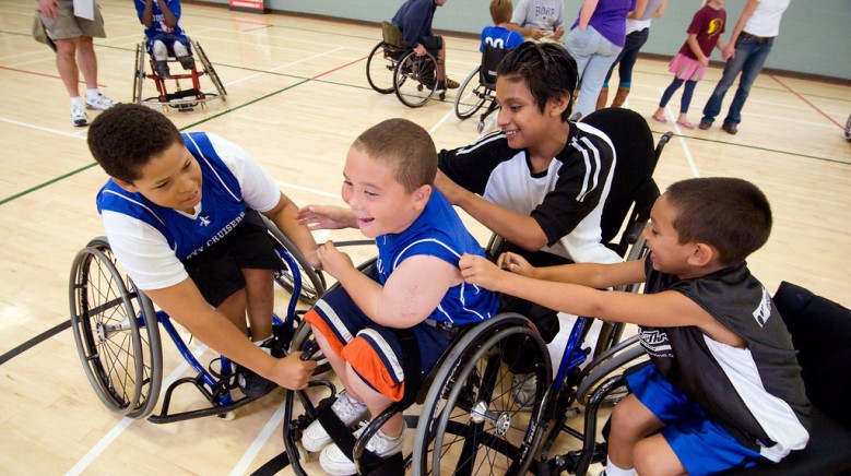a group of smiling youth athletes surround a teammate and pat him on the back