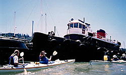 Two kayaks pass in front of a ship