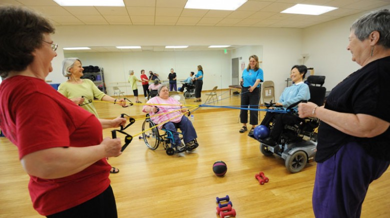 BORP adaptive fitness class with six woman in a circle pulling resistance bands