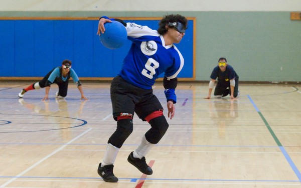 Number 9 about to shot a goalball as his oppenents await the shot at the far end of the floor