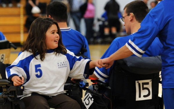 A BORP power soccer player gives a fist bump to an opposing coach