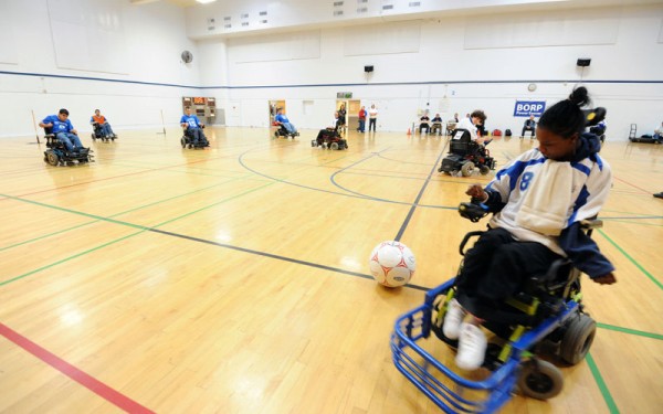 A player prepares to put a ball in play with a view of the whole court during a power soccer match