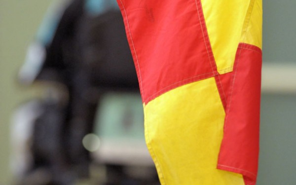 A close up of a power soccer referee's flag with a soccer ball in the backgroud
