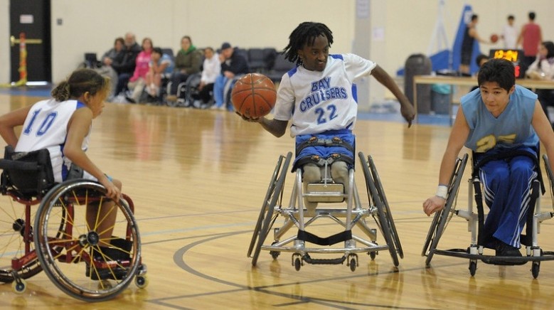 A youth wheelchair basketball player prepares to pass the ball