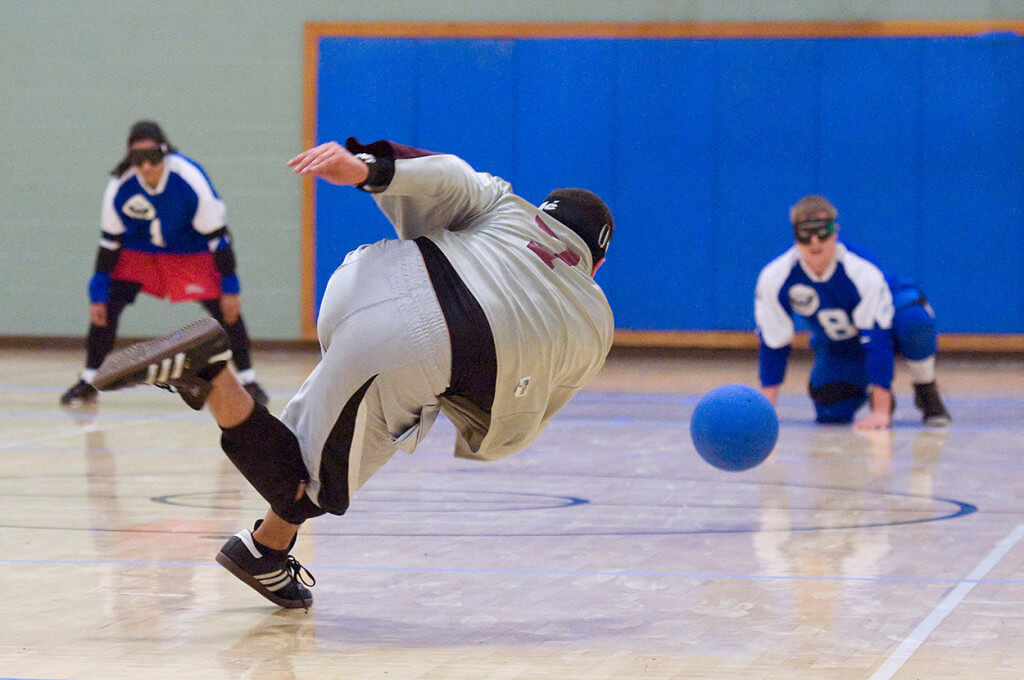 A goalball player follows through after throwing towarsds his oppenents