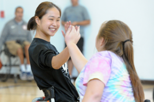 Two girls high five while playing wheelchair basketball at BORP's 2017 Opening Day. Image Courtesy of Scott Goodman