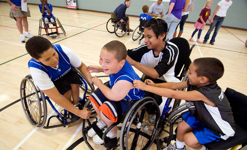 a group of smiling youth athletes surround a teammate and pat him on the back