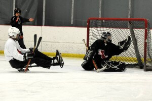 A goalie makes a save while an opposing player looks on