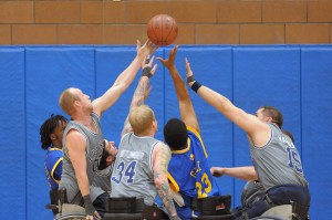 Five players reach for a basketball above them