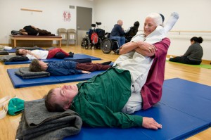 A BORP fitness instructor assists a class participant in an adaptive yoga class