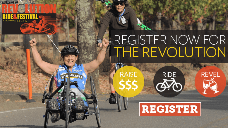 Register Now for the Revolution -- a hand cyclist raises her arms in the air to celebrate during the Rev.