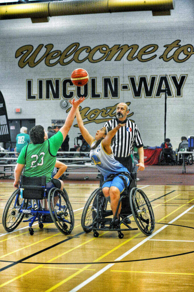 Two kids playing wheelchair basketball; tip off
