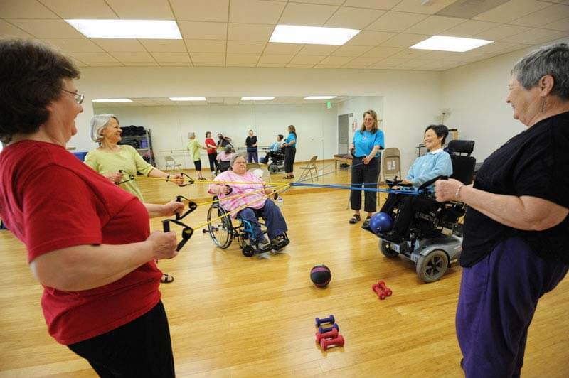 Group of people standing and in wheelchairs working out at BORP fitness center