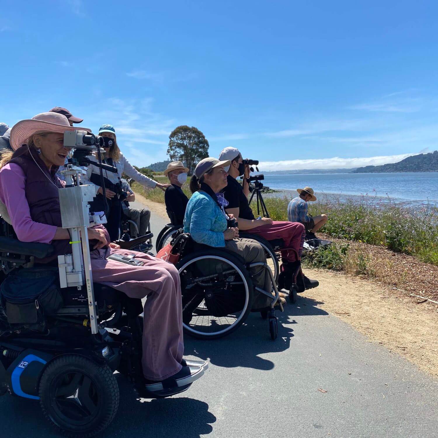 Group of people in wheelchairs use binoculars to look at birds