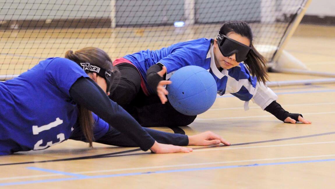 Two young women goalball players struggle to get the ball
