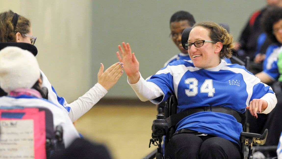 Two women power soccer players high-five each other