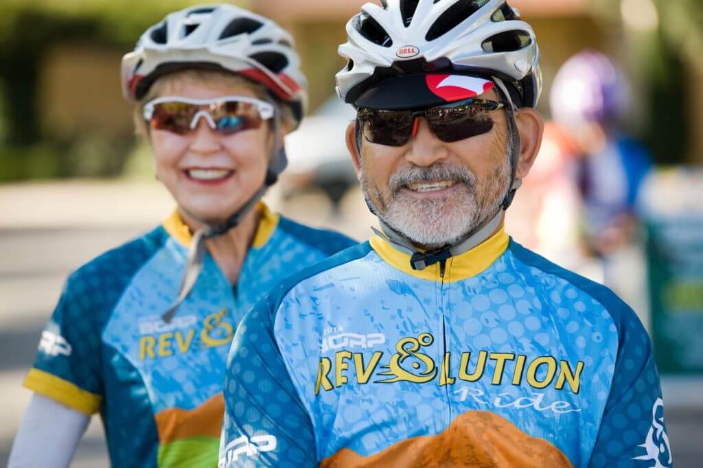 Man and woman wearing Revolution ride jerseys smile