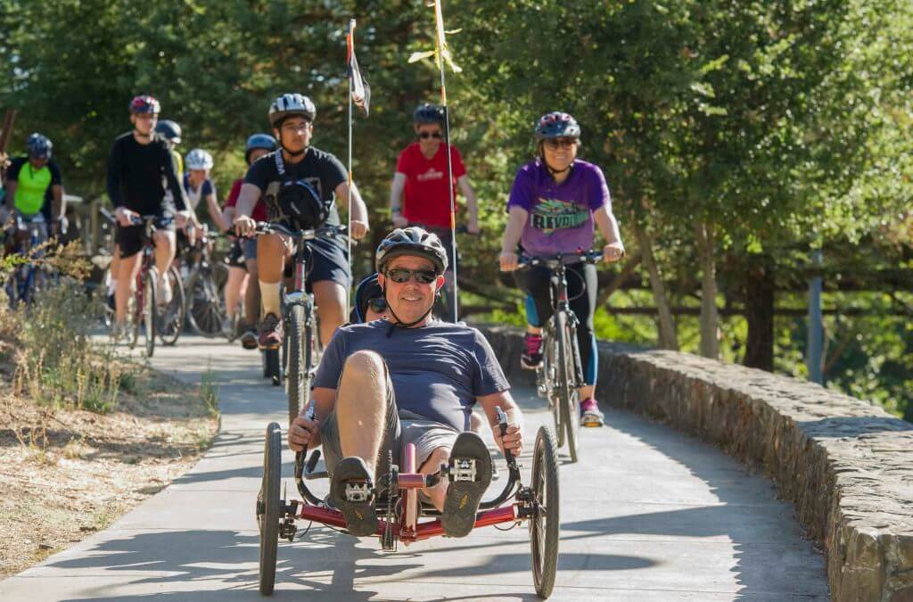 Man on recumbent bike smiles as he leads group of cycists