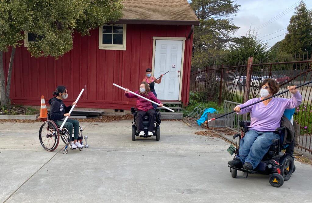 Three female participants in outdoor fitness class working out