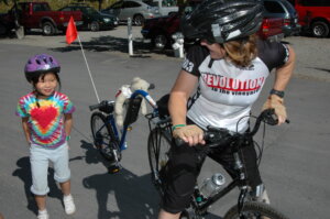 Person with a trail-a-bike wearing a 2003 Revolution Ride Jersey