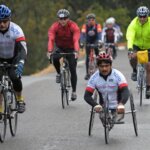 Two cyclists, one in a hand-cycling riding wearing 2008 Revolution Ride jerseys.
