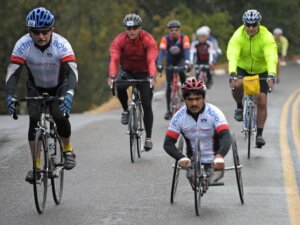 Two cyclists, one in a hand-cycling riding wearing 2008 Revolution Ride jerseys.