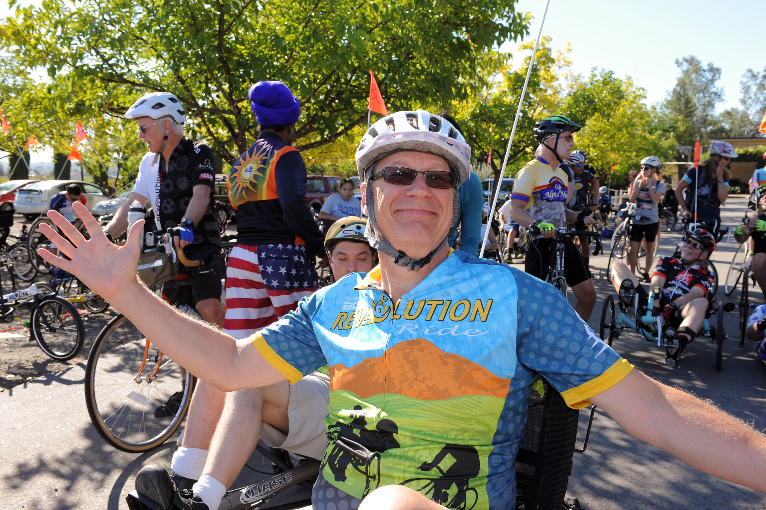 Man in a recumbent cycle wearing the 2014 Revolution Ride jersey with a big smile and arms outstretched.