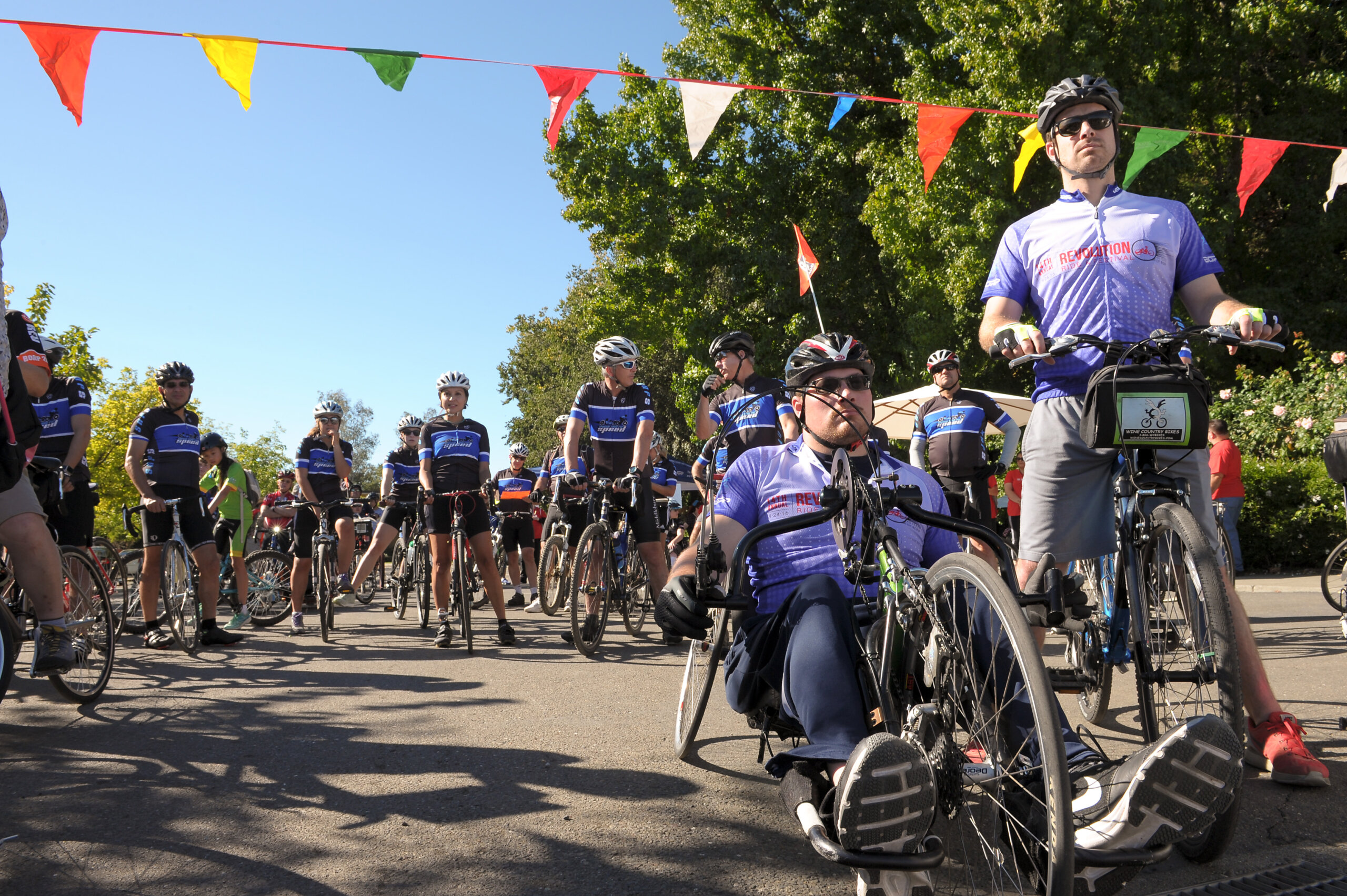 Two men, one on a hand-cycle and the other on a bicycle, both wearing the 2016 Revolution Ride jersey.