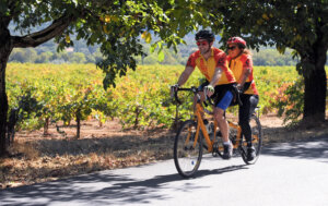 Two people riding a tandem bicycle, both wearing the 2017 Revolution Ride jersey.