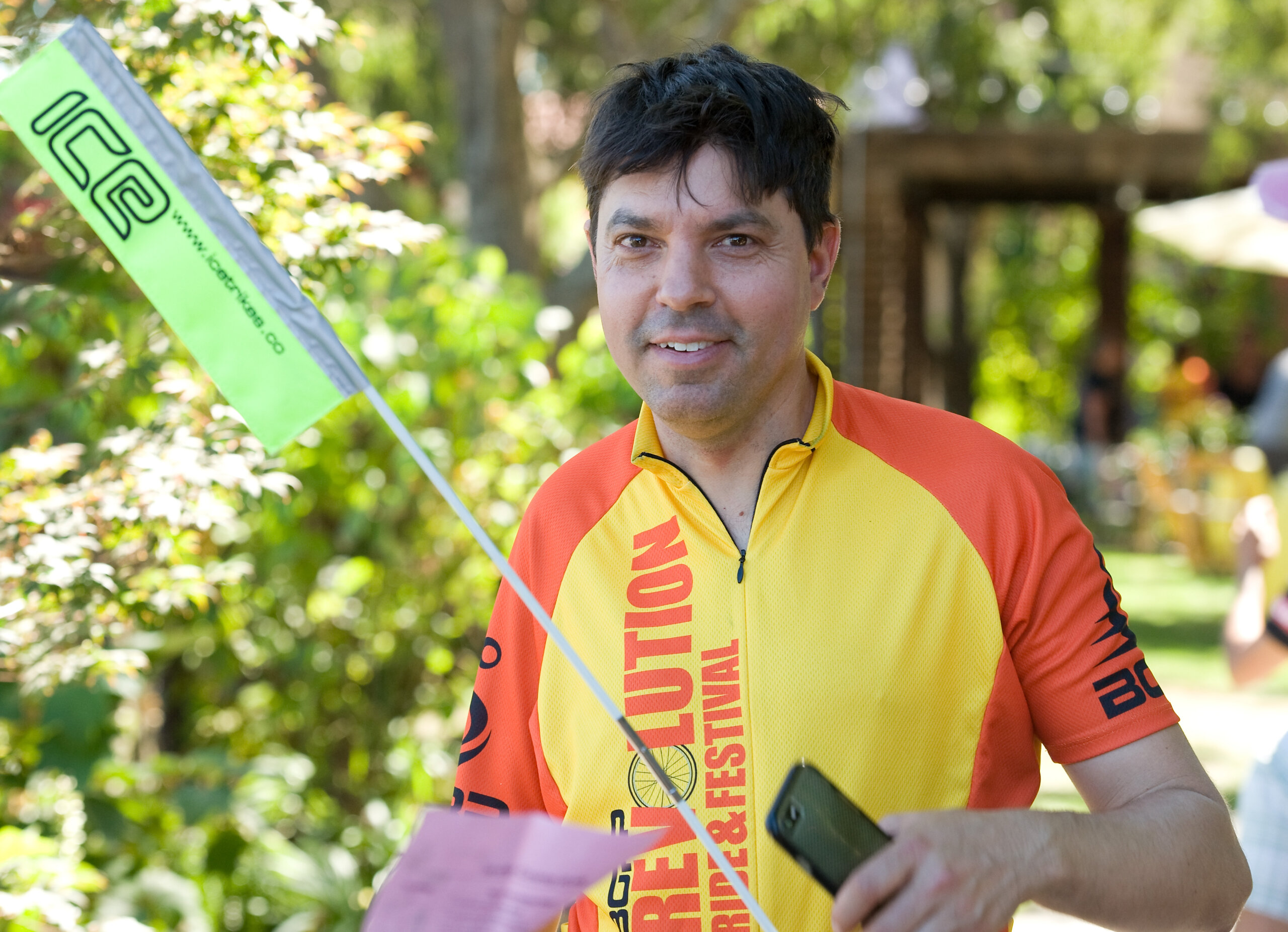 A young man wearing the 2017 Revolution Ride jersey and holding a cyclist visibility flag.