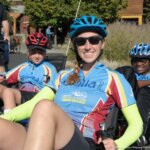 A woman in a recumbent cycle wearing the 2018 Revolution Ride jersey, two young men behind her are also wearing the 2018 jersey and in recumbent cycles