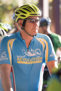 A man in a bike helmet wearing a 2019 Revolution Ride jersey.