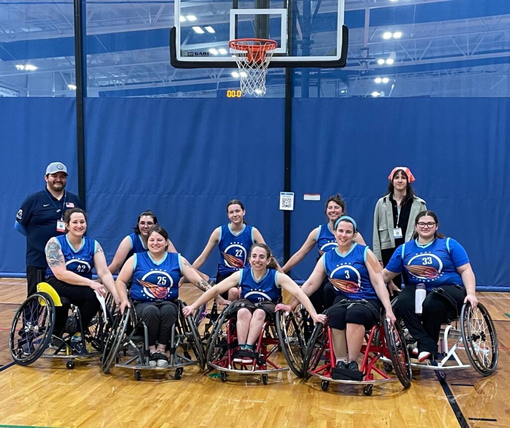 The meteorites, a group of 8 players, pose in sports chairs after their last game with arms linked and smiles.