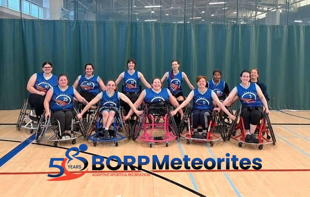 Ten basketball players using wheelchairs and wearing blue jerseys and one coach pose in a gym. Text underneath reads BORP Meteorites