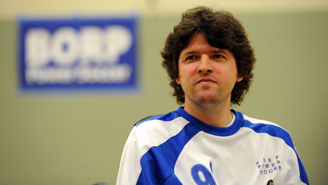 Face and shoulders of John Madigan - a white man with brown hair wearing a jersey that reads #9