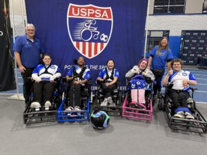 Photo of five power wheelchair using teammates wearing BORP Shockers jerseys and two non-wheelchair-using coaches